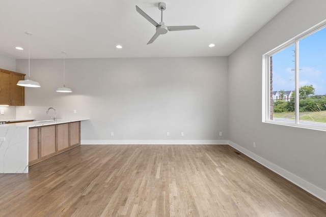 kitchen featuring sink, hanging light fixtures, light hardwood / wood-style flooring, ceiling fan, and decorative backsplash