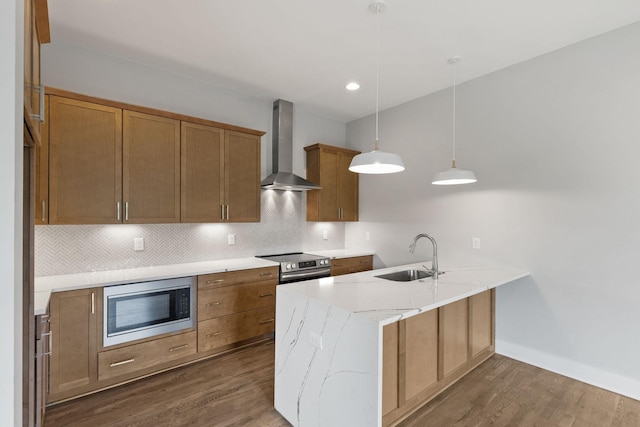 kitchen featuring stainless steel electric stove, decorative light fixtures, built in microwave, sink, and wall chimney range hood