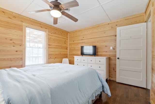 bedroom with dark hardwood / wood-style flooring, ceiling fan, and wooden walls