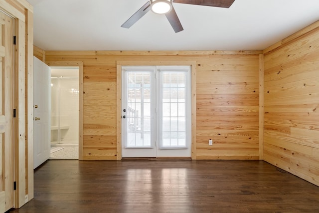 unfurnished room featuring ceiling fan, dark hardwood / wood-style flooring, and wood walls