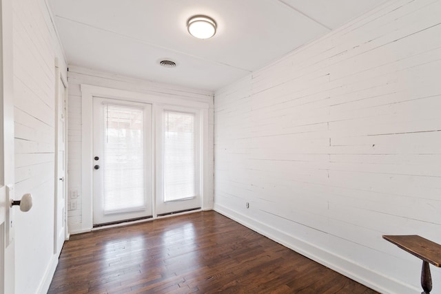 interior space featuring dark wood-type flooring and wooden walls