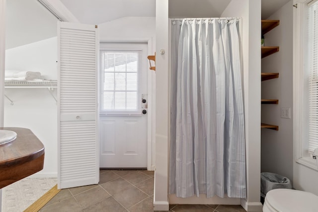 bathroom with lofted ceiling, tile patterned floors, and toilet