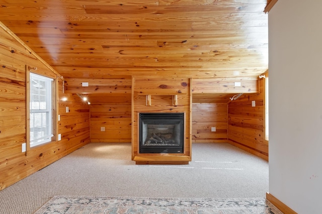 unfurnished living room featuring vaulted ceiling, wood ceiling, carpet floors, and wood walls