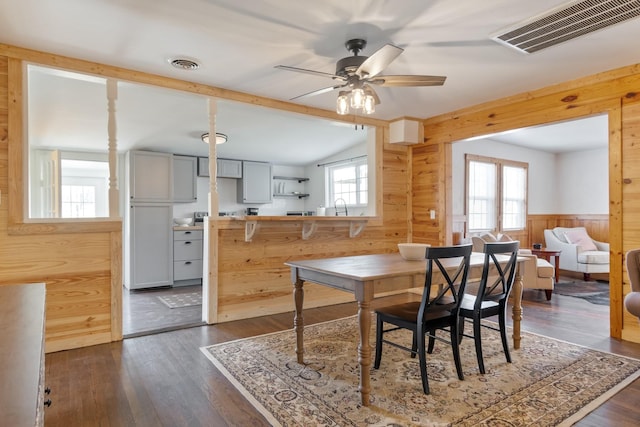 dining space with dark hardwood / wood-style floors, a wealth of natural light, and wood walls