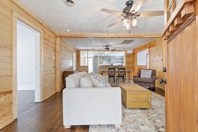 living room with dark hardwood / wood-style flooring, ceiling fan, and wooden walls