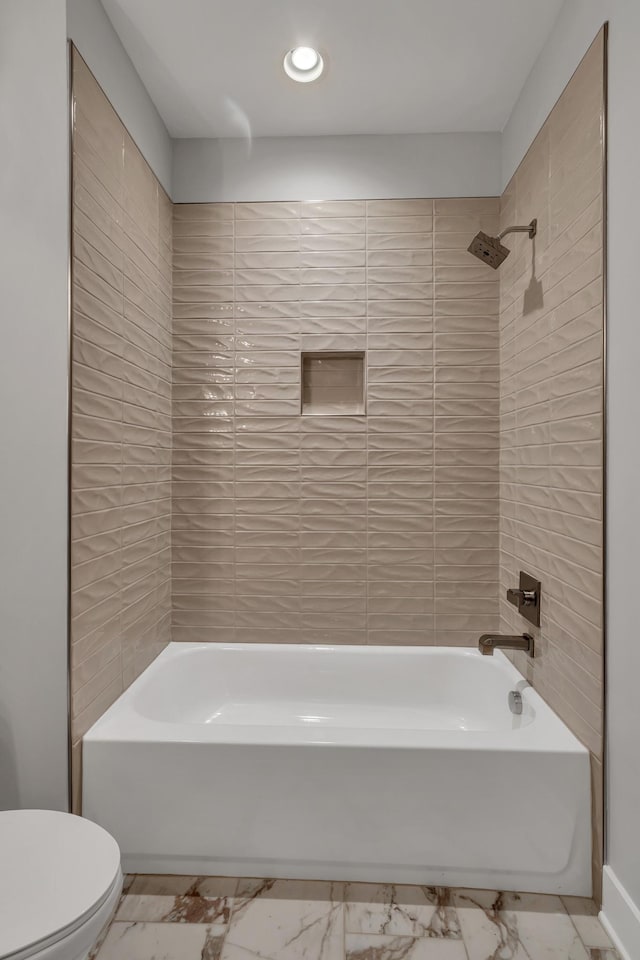 bathroom featuring tiled shower / bath combo and toilet