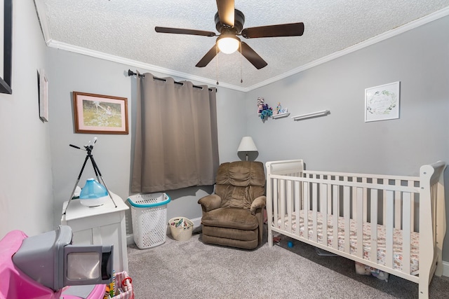 carpeted bedroom featuring a nursery area, ceiling fan, crown molding, and a textured ceiling