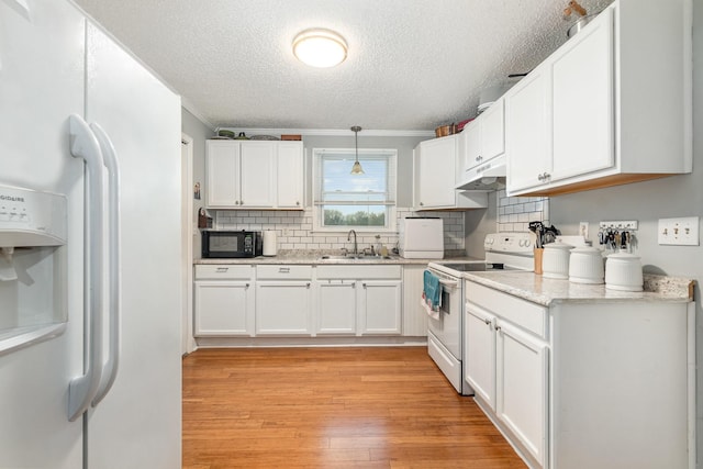 kitchen featuring white cabinetry, sink, hanging light fixtures, light hardwood / wood-style floors, and white appliances