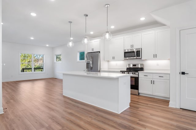 kitchen with decorative light fixtures, stainless steel appliances, and white cabinets