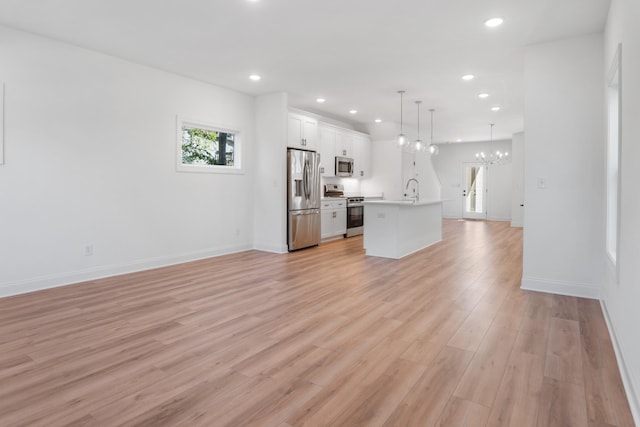 unfurnished living room with sink, light wood-type flooring, and a notable chandelier