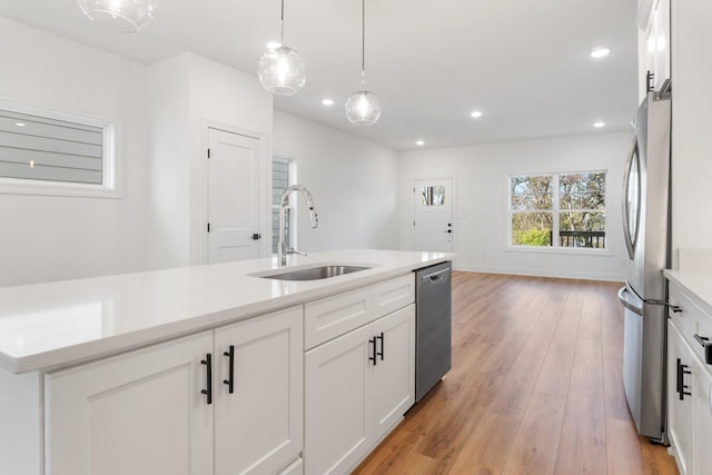 kitchen with pendant lighting, appliances with stainless steel finishes, sink, and white cabinets