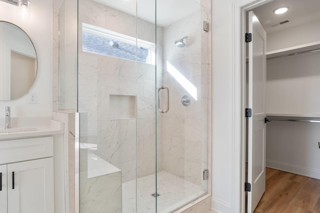 bathroom with hardwood / wood-style flooring, vanity, and a shower with shower door