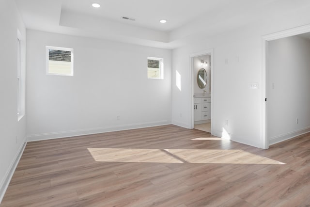 spare room featuring light wood-type flooring and a tray ceiling