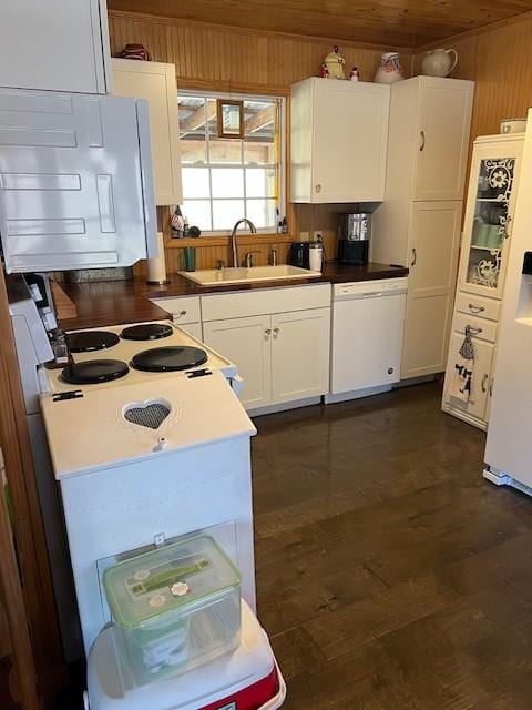 kitchen featuring sink, wooden walls, dark hardwood / wood-style flooring, white appliances, and white cabinets