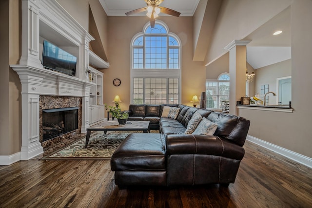 living room with a high ceiling, ceiling fan, hardwood / wood-style floors, and a fireplace