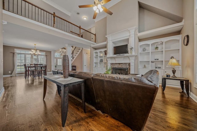 living room with crown molding, a towering ceiling, ceiling fan with notable chandelier, and hardwood / wood-style floors