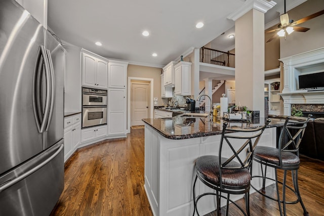 kitchen with sink, a breakfast bar, appliances with stainless steel finishes, white cabinets, and kitchen peninsula