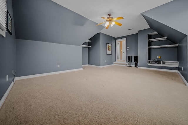 additional living space with vaulted ceiling, carpet floors, ceiling fan, and built in shelves