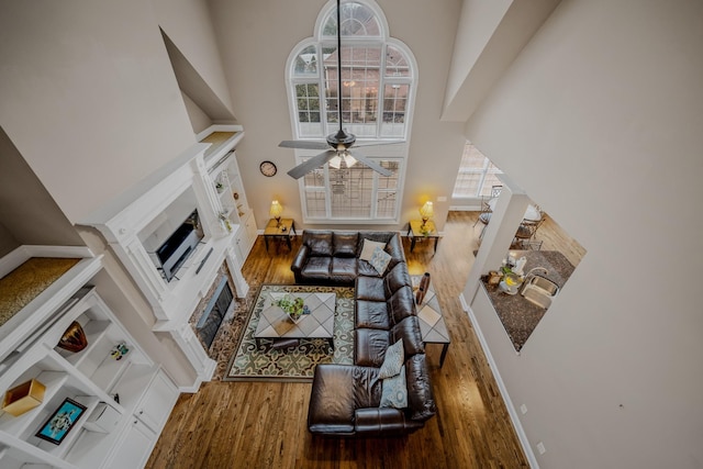 living room with a high ceiling, hardwood / wood-style flooring, sink, and ceiling fan