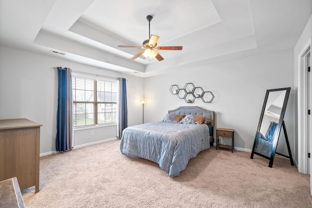 carpeted bedroom featuring ceiling fan and a tray ceiling