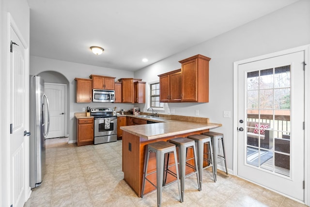 kitchen featuring appliances with stainless steel finishes, sink, a kitchen bar, and kitchen peninsula