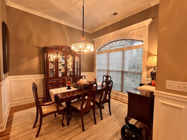 dining room with crown molding, a chandelier, and light wood-type flooring