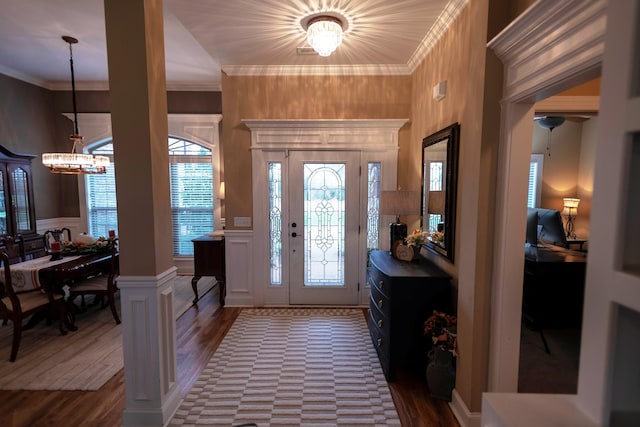 entrance foyer with an inviting chandelier, ornamental molding, and dark hardwood / wood-style floors