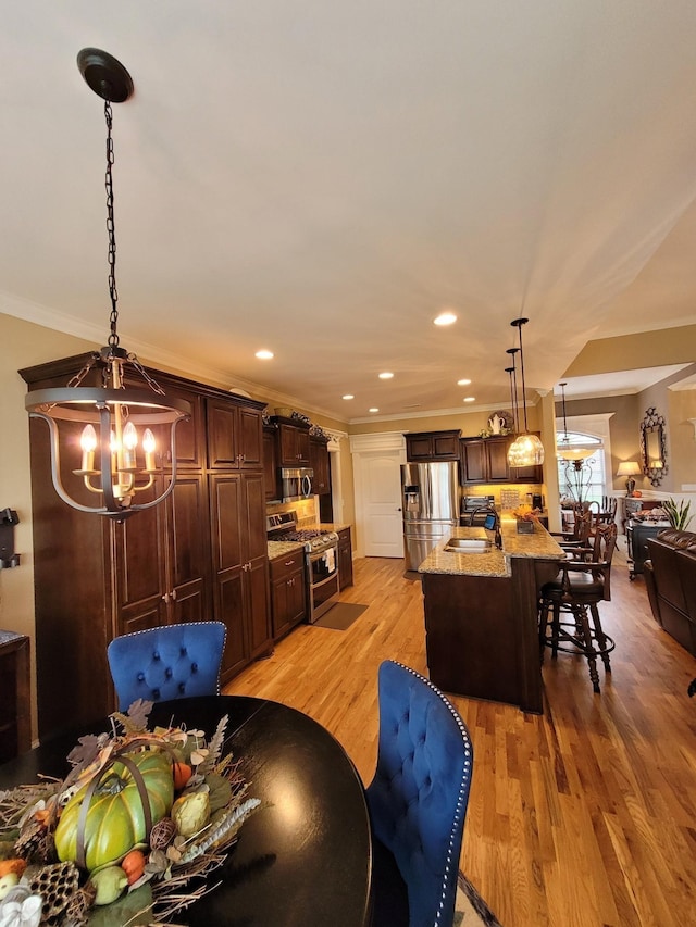 dining space with crown molding, sink, a chandelier, and light wood-type flooring