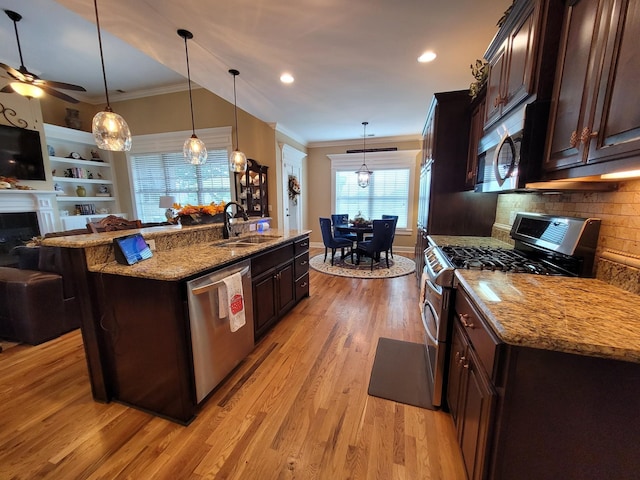 kitchen with dark brown cabinetry, sink, an island with sink, pendant lighting, and stainless steel appliances