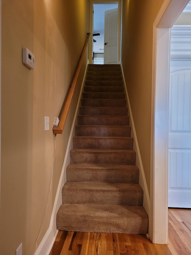 stairway with baseboards and wood finished floors