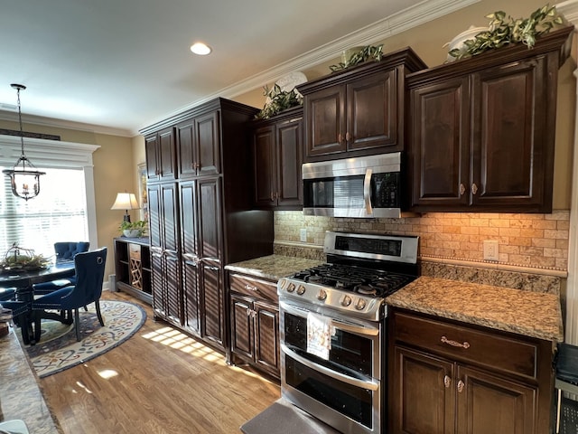 kitchen featuring stainless steel appliances, decorative light fixtures, dark brown cabinets, and light wood-type flooring