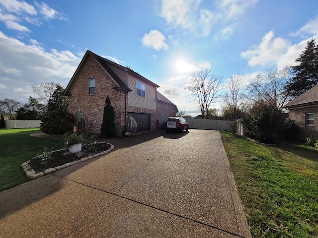 view of side of home with driveway, an attached garage, fence, a yard, and brick siding