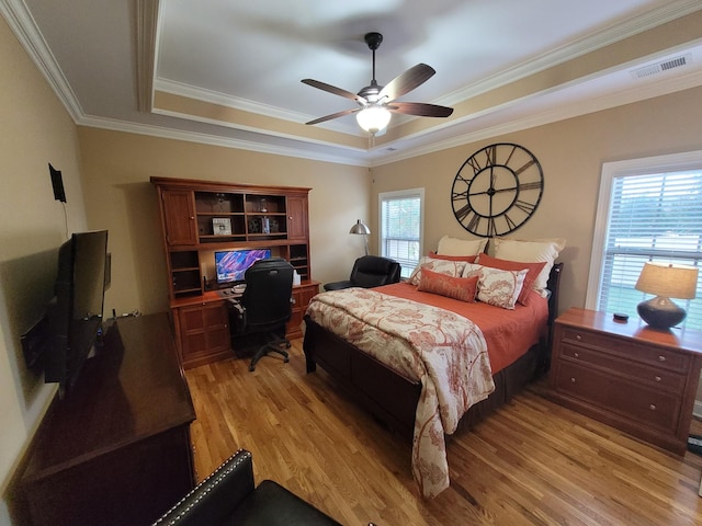 bedroom with ornamental molding, a raised ceiling, ceiling fan, and light wood-type flooring