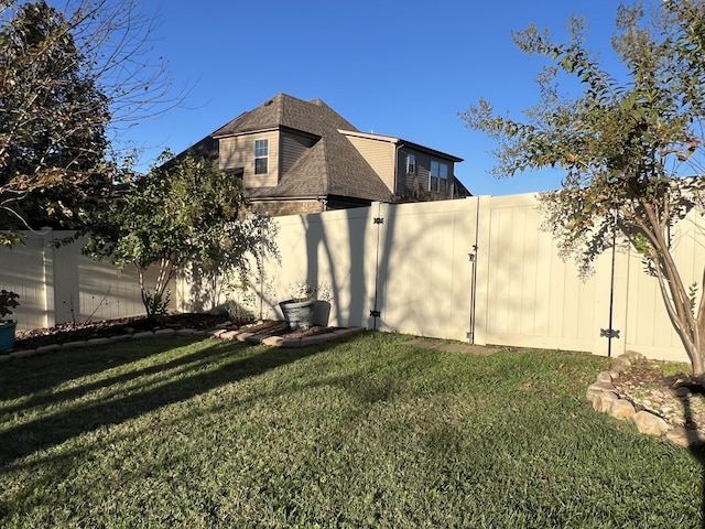 exterior space with a yard, roof with shingles, and a fenced backyard