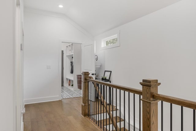 corridor with hardwood / wood-style flooring and lofted ceiling