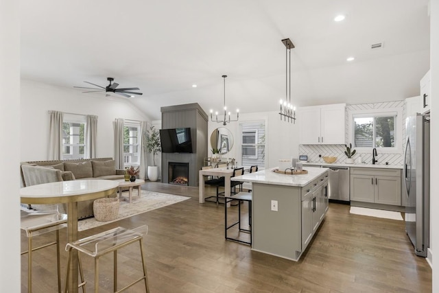 kitchen with appliances with stainless steel finishes, a breakfast bar, decorative light fixtures, lofted ceiling, and a center island