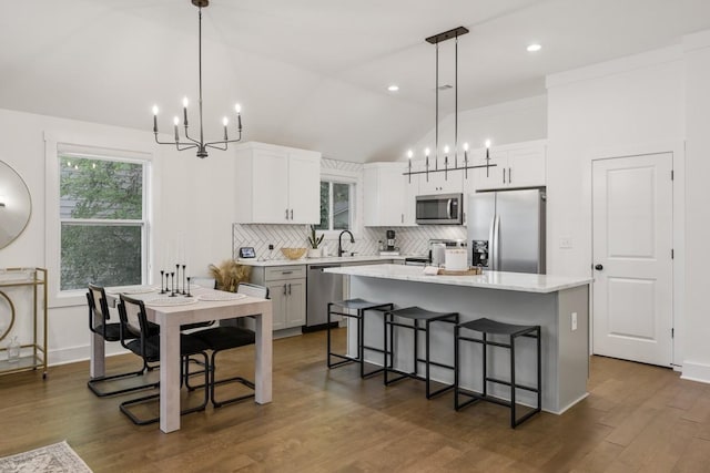 kitchen featuring sink, white cabinetry, hanging light fixtures, a kitchen island, and stainless steel appliances