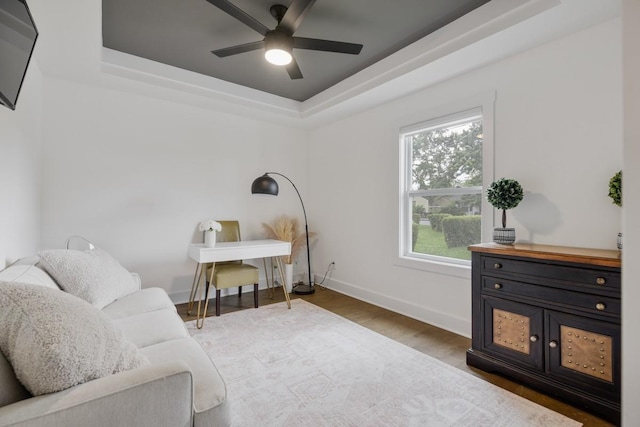 sitting room featuring hardwood / wood-style flooring, a raised ceiling, and ceiling fan