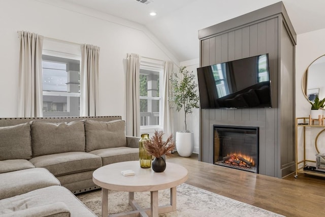 living room featuring lofted ceiling, a fireplace, and light hardwood / wood-style flooring