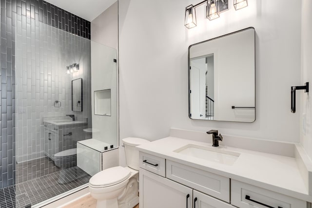 bathroom with tiled shower, vanity, and toilet