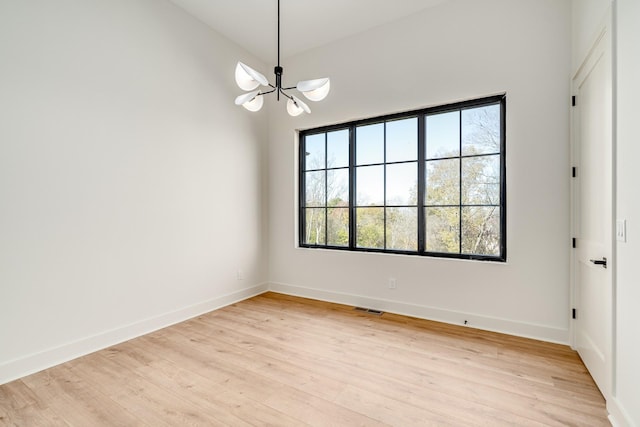 empty room featuring an inviting chandelier and light wood-type flooring