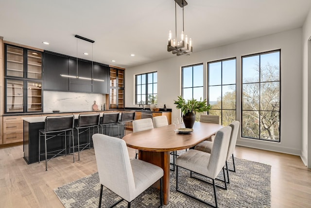 dining space with a notable chandelier, light hardwood / wood-style floors, and sink