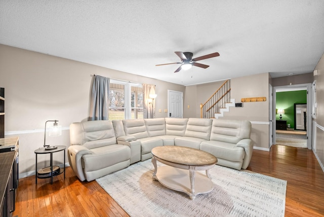 living room featuring ceiling fan, wood-type flooring, and a textured ceiling