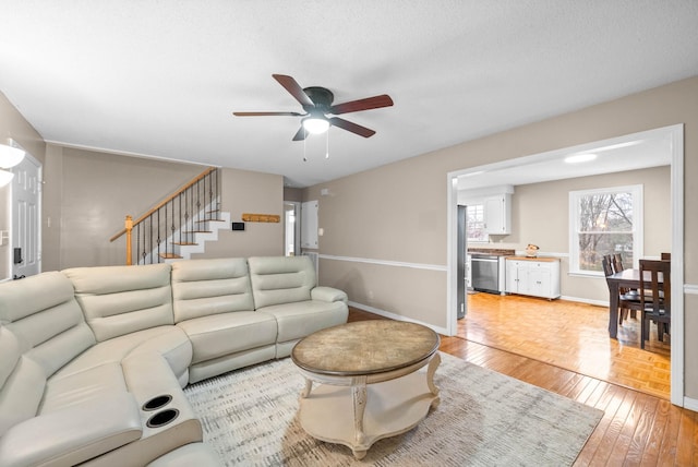 living room featuring ceiling fan, hardwood / wood-style flooring, and a textured ceiling