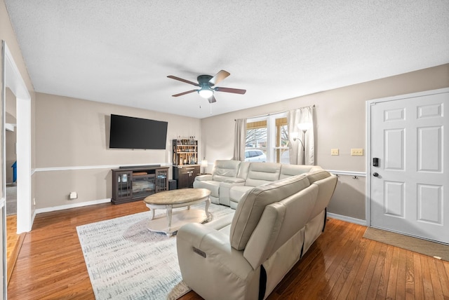 living room featuring ceiling fan, hardwood / wood-style floors, and a textured ceiling