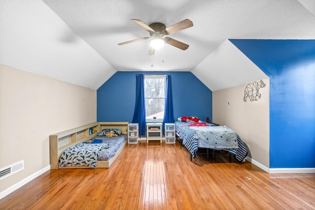 bedroom featuring hardwood / wood-style flooring, lofted ceiling, a textured ceiling, and ceiling fan