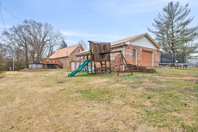 view of play area with a pool, a yard, and a trampoline