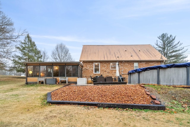 rear view of property featuring a yard, a covered pool, and a sunroom