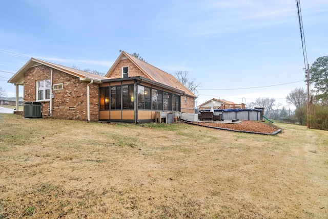 back of property featuring a sunroom, a covered pool, a yard, and central air condition unit