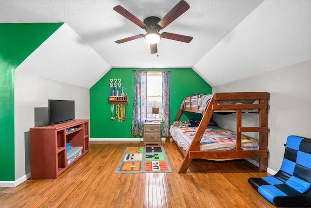 bedroom featuring hardwood / wood-style flooring, vaulted ceiling, and a textured ceiling